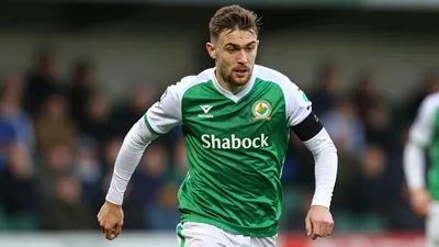 A tight action shot of an anonymous Shamrock Rovers player in a green jersey with white sleeves, running with the ball