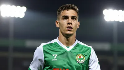 A tight action crop of a young, fit, anonymous Shamrock Rovers player in a green jersey with white sleeves and a white...