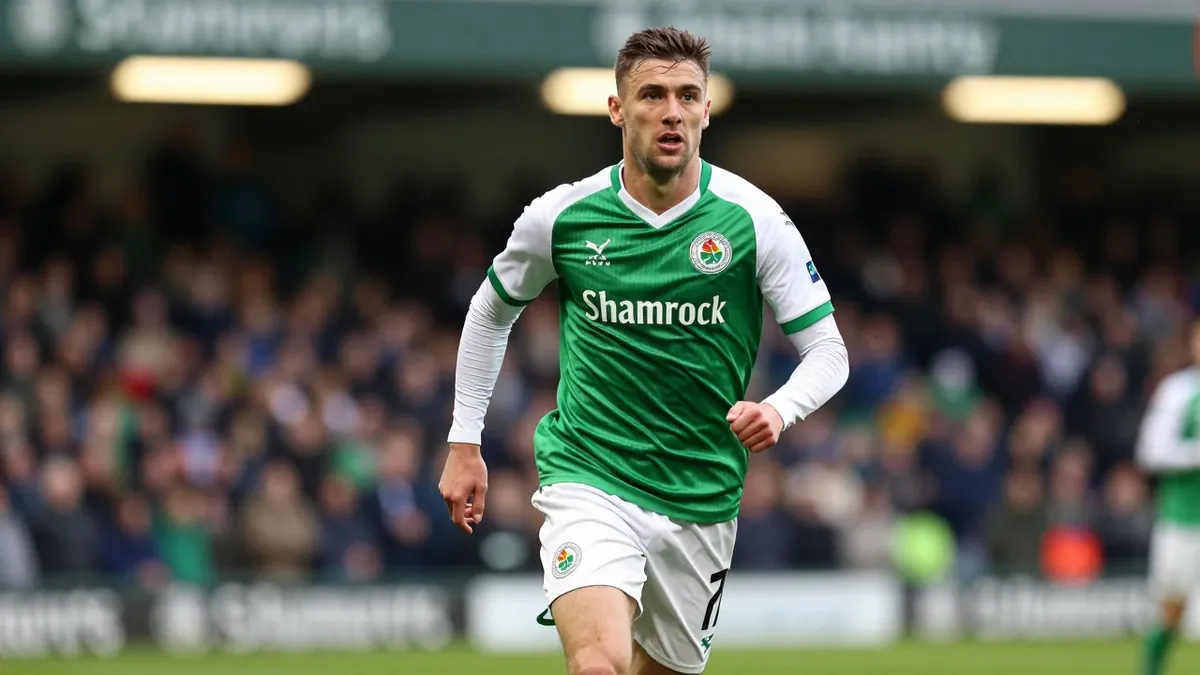 A tight, waist-up shot of a Shamrock Rovers player in a green jersey with white sleeves, with a white kit and green...