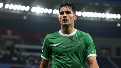 Mid-30s, lean midfielder, head-and-shoulders, drenched in sweat, eyes focused, dark green shirt with white trim, plain...